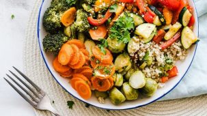 Alimentation alcaline : un plat est posé sur une table en bois à côté d'une fourchette. Il est rempli de légumes, de quinoa et d'herbes fraîches.