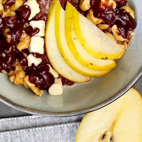 Petit déjeuner végétalien sans gluten : bol de sarrasin avec des poires, des noix, du chocolat et des morceaux de noix de coco