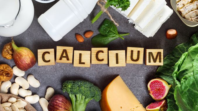 Aliments riches en calcium sur une table en bois : fromages, amandes, haricots, légumes verts, figues, etc.