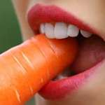 Gros plan sur la bouche d'une femme qui mange une carotte.
