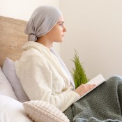 Femme blanche lisant un livre dans sa chambre après une chimiothérapie.