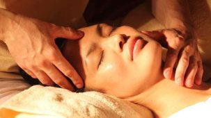 Femme détendue pour une séance de rélexologie faciale (dien chan). Les mains du reflexologue sont sur son visage pour favoriser le bien-être.