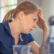 Femme anxieuse au travail. Elle se tient le front, assise devant son travail à accomplir.