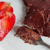 Histaminose et chocolat. Part de fondant au chocolat IG bas et sans gluten : on aperçoit une fourchette avec du gâteau et des fraises sur une assiette