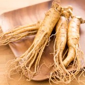 Trois racines de ginseng sur un plateau en bois.