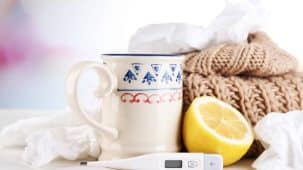 Grippe : on aperçoit une infusion à côté de mouchoirs, d'un demi-citron, d'un thermomètre et d'une écharpe