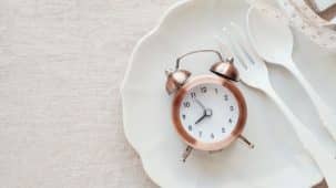 Jeûne : horloge, fourchette et cuillère posées dans une assiette sans aliments. Cette image représente l'absence de nourriture pendant une période de temps.