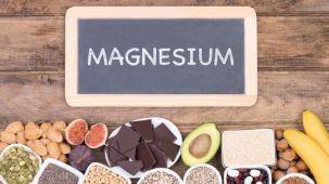 Des aliments qui contiennent du magnésium sont disposés sous un tableau en ardoise sur lequel est écrit MAGNESIUM. L'ensemble est posé sur un parquet en bois.
