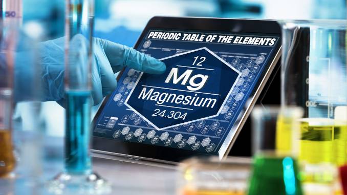 Main d'un scientifique montrant le magnésium (élément chimique Mg) sur le tableau périodique des éléments visible sur une tablette.