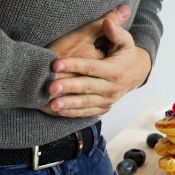 Zéolithe et reflux gastriques : un homme qui se tient le ventre avec les deux mains sur son ventre. Plan de près.