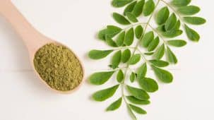 Feuille et poudre de Moringa en gros plan disposés sur une table blanche