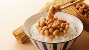 Un plat de natto riche en nattokinase dans un bol rayé servi avec du riz blanc.