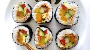 6 makis en gros plan sur fond blanc. Sushis (makis) colorés grâce aux ingrédients : algue, riz, concombre, avocat, potiron, poivron, graines de sésame et tapenade de tomates.