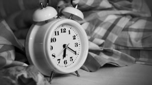 Horloge réveil posée sur un lit. Photo en noir et blanc