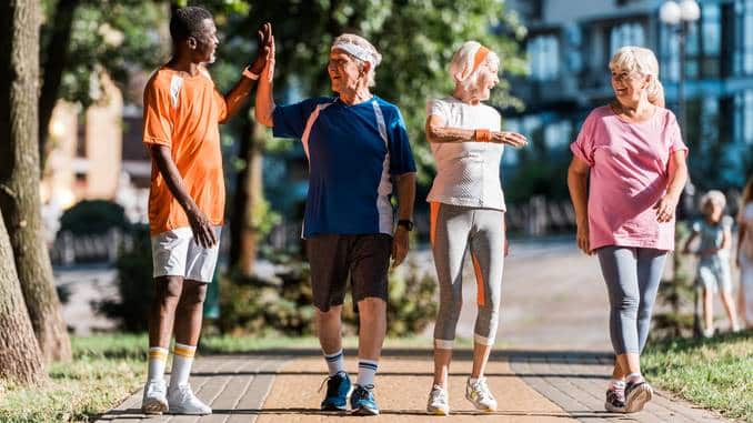 Sarcopénie : un groupe de seniors marchent ensemble dans la rue et se tapent dans la main