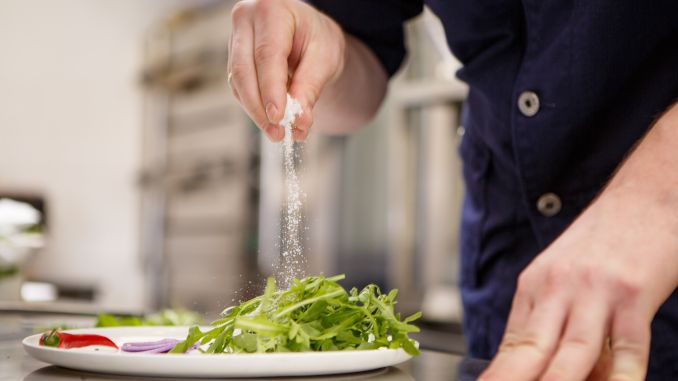 Sel versé sur une salade, directement de la main d'un chef.