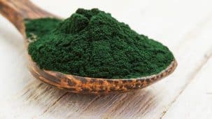 Spiruline sous forme de poudre posée sur une table en bois