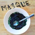 Masque de spiruline : recette réalisée dans un bol blanc, les ingrédients mélangés par une cuillère. Masque écrit sur le support en bois, avec la recette de spiruline.