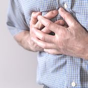 Chondroïtine et cœur : gros plan sur la poitrine d'un homme en chemise bleue. Il pose sa main sur son cœur et semble avoir un problème cardiovasculaire car sa main est crispée.