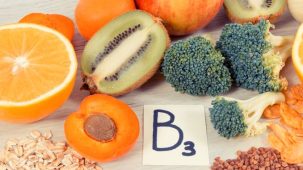 Aliments riches en vitamine B3 : un kiwi, du brocolis, un abricot et des graines de sarrasin et des flocons d'avoine sont sur une table.