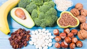 Aliments riches en vitamine B6 : on aperçoit des légumineuses. des légumes, des oléagineux et des fruits sur une table bleue.